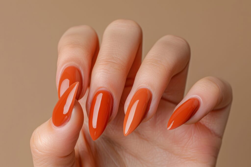 Home 10 womans hand with long almond shaped nails painted with bright orange nail polish